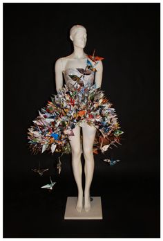 a white mannequin wearing a dress made out of many different types of papers