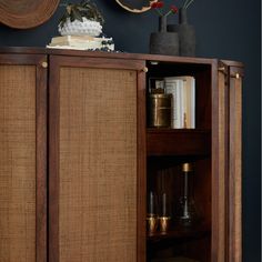 a wooden cabinet with books and vases sitting on it's shelf next to a clock