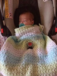 a baby in a car seat with a blanket