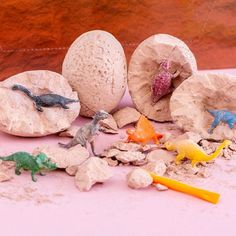 some toys are laying on the ground next to rocks and eggs that look like dinosaurs