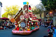 a large gingerbread house float on a street in front of a group of people