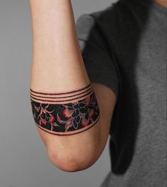 a woman's arm with a black and red flower tattoo on the left wrist