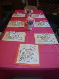 the table is set up with cards and pencils to draw cupcakes on