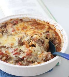 a casserole dish with meat and cheese in it on a blue napkin next to a book