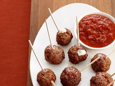 several meatballs on skewers with sauce and toothpicks sitting on a plate