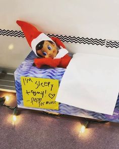 an elf is sitting on top of a box with a sign attached to it that says i'm creepy happy peppermint