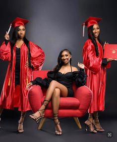 two women in graduation gowns sitting on a red chair and posing for the camera