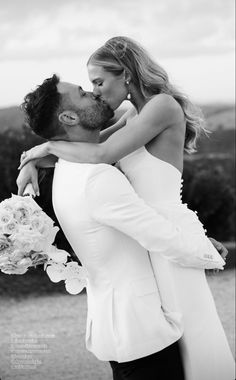 a bride and groom kissing each other in black and white