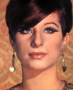 a woman with short hair and earrings on her head is looking at the camera while wearing an evening dress