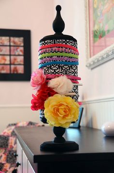 a multicolored cake with flowers on it sitting on top of a black table