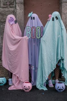 three people dressed up as ghostes and pumpkins in front of a door with boo written on it