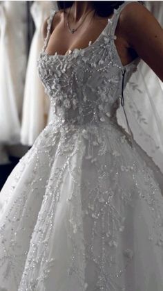 a woman in a wedding dress is looking at the other brides dresses on display