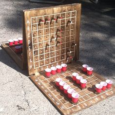 an old board game set up on the sidewalk with red cups in front of it