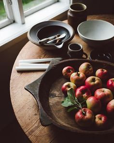 apples are in a bowl on a wooden table