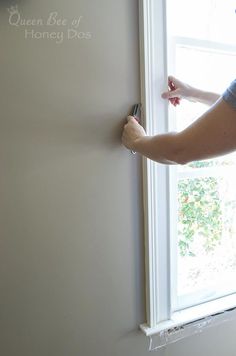 a woman is painting the wall with white paint