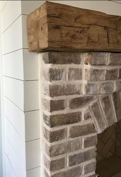 a brick fireplace with a wooden mantel above it