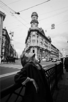 black and white photograph of woman looking up at building