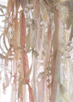 a white chandelier with feathers and beads hanging from it's sides in front of a window