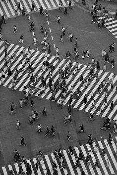 an aerial view of people walking across a crosswalk in the middle of a city