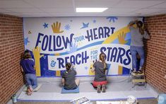 four people sitting in front of a sign that says follow your heart and reach for the stars