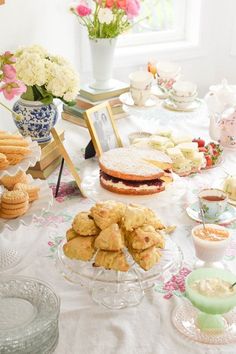 a table full of pastries and desserts with flowers in vases behind them