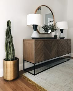 a living room with a large mirror and two lamps on top of the sideboard