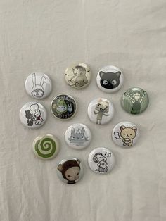 a bunch of buttons sitting on top of a white sheet with animals drawn on them