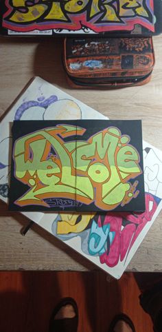 two skateboards sitting next to each other on top of a wooden table with graffiti written on them