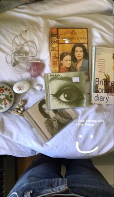 there are many books and other items on the bed with someone's feet up