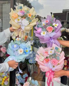 three people holding bouquets of flowers in front of a store window with their hands on them