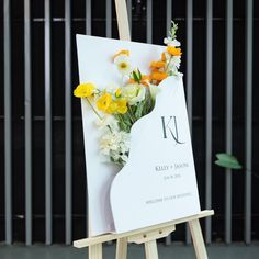 an easel with flowers on it sitting in front of a building