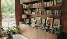 a room with bookshelves and pictures on the wall next to a vase filled with flowers