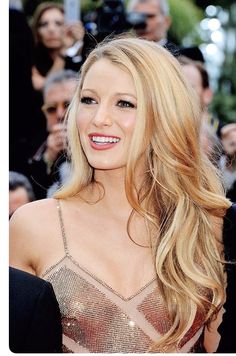 a woman with long blonde hair standing in front of photographers