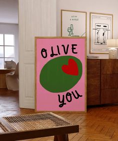 a pink and green poster with the words olive you on it in front of a wooden table