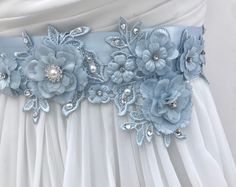 "Exquisite vintage chic hand sculpted floral lace bridal sash with 3D embroidered flowers, sparkling Swarovski crystals & Swarovski Pearls. This ultra romantic wedding sash is from my new Luxe Collection of intricately designed one of a kind heirloom quality wedding sashes for your most important day. READY TO SHIP DETAILS: * The beaded piece measures 3\" Wide (4\" lwhere flower drops down) ) by 15\" long * Hand sewn onto 2\" wide luxurious Bridal Blue French imported double faced satin ribb Blue Wedding Dress With Sashes, Lace Bridal Belt For Ceremony, Lace Bridal Belt With Sashes For Wedding, Elegant Bridal Belt With Handmade Flowers For Weddings, Beaded Bridal Sash, Sash Wedding Dress, Statement Earrings Wedding, Crystals Swarovski, Wedding Dress Sash