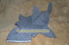 a knitted shark hat laying on top of a bed