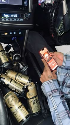 a man holding a cell phone in his hand next to a bunch of beer cans