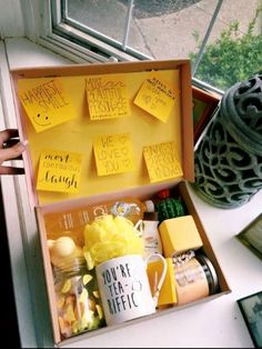 an open box with sticky notes on the lid and writing on it, sitting next to a window