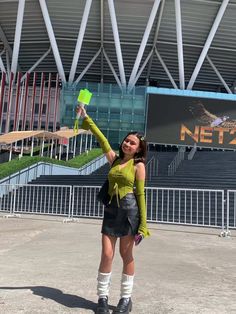 a woman holding up a green cup in front of a stadium