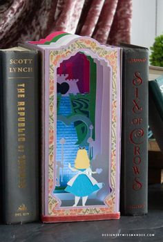 three bookends are sitting on a table with books in front of them and one has an image of a woman