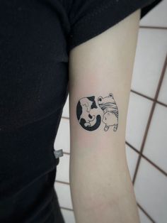 a woman's arm with a small black and white cow tattoo on the left inner arm