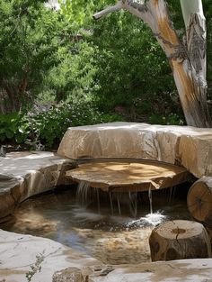 a water feature in the middle of a garden with trees and rocks around it, surrounded by greenery