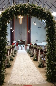 an aisle decorated with white flowers and greenery for a wedding ceremony in a church