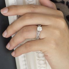 a woman's hand with a diamond ring on her finger and an engagement band