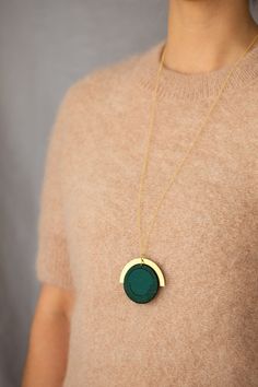 "I have designed the pieces in this collection to be easy to wear with anything. I wanted to focus on the shapes and composition of the pieces themselves as opposed to the stitches on them. This circular pendant is made from Forest Green cotton which has been interfaced to provide structure. I have bound the edges in a band with a matching embroidery thread in Forest Green. This is joined to a brass arc which is hung from a long 30\" chain of Gold Vermeil . The pendant measures 50x50mm. All find Modern Necklace With Detachable Round Pendant, Modern Necklace With Detachable Pendant, Modern Green Circular Jewelry, Modern Handmade Circular Necklace, Modern Green Necklace With Round Pendant, Modern Green Round Pendant Necklace, Chain Of Gold, Matching Embroidery, Circle Pendant