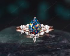 an engagement ring with a blue and white fire opal surrounded by smaller round diamonds