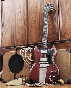 an electric guitar sitting on top of a hard wood floor next to two amps