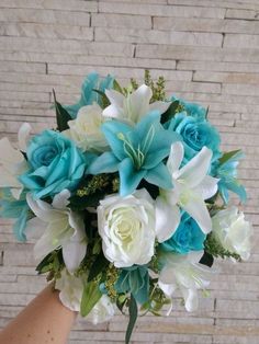 a bridal bouquet with blue and white flowers in front of a brick wall,