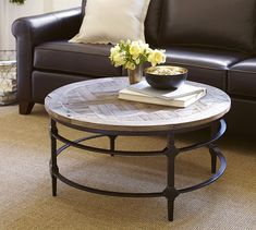 a living room with a couch, coffee table and flower arrangement on the center table