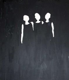 three people standing in front of a black wall with white paint on it and one person has long hair